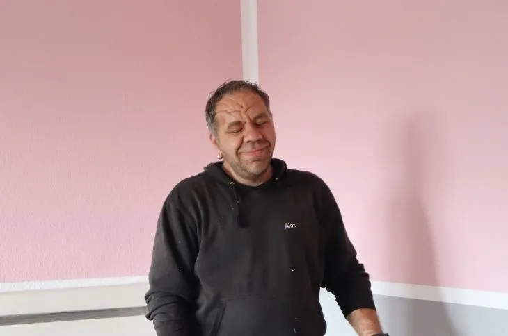 umzugshelfer steht in raum mit rosa wand und pause